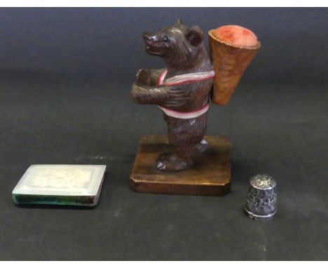 An early 20th Century black forest pin cushionModelled in the form of a standing bear holding a hallmarked silver thimble, he