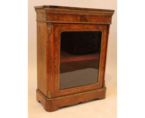 A Victorian walnut veneered and gilt metal mounted pier cabinetWith single glazed door and shelved interior, raised on a plin