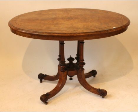 A Victorian burr walnut and inlaid oval topped loo tableOn four leg pedestal with scrolled feet and castors, height 70cm, len