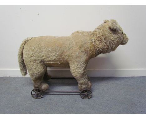 An early 20th Century plush pull along bear, humped back, possibly Steiff, worn, 91cm long 