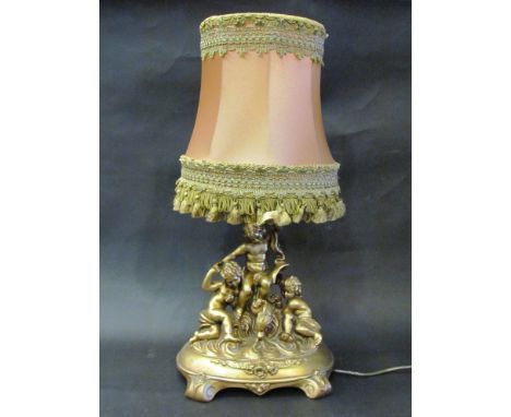 A gilded cherubic table lamp with tasselled shade, 48cm tall 