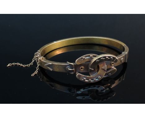 A Victorian stiff-hinged bangle with two interlocked horseshoes, stamped 15ct, 23.8g