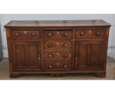 18th century oak dresser base with three short drawers over three dummy drawers flanked by cupboards, with carved decoration 