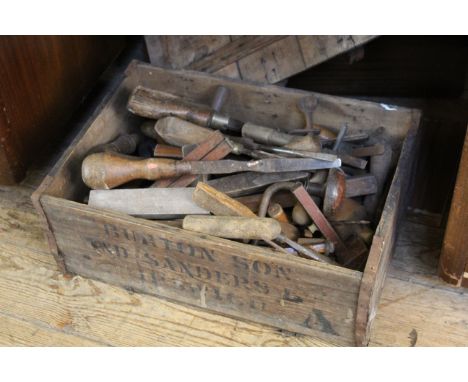 A vintage pine box containing an assortment of hand tools