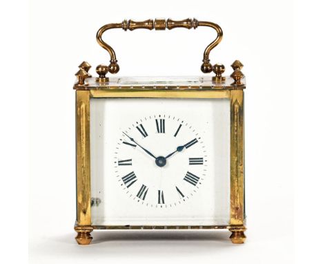 A brass carriage clock, with Roman numerals to the dial and raised on short feet and complete with carrying case.  Height exc