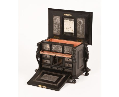 A Victorian ebonised cabinet, with carved figureheads to each side, the lid lifting to a mirrored centre and with thin metal 