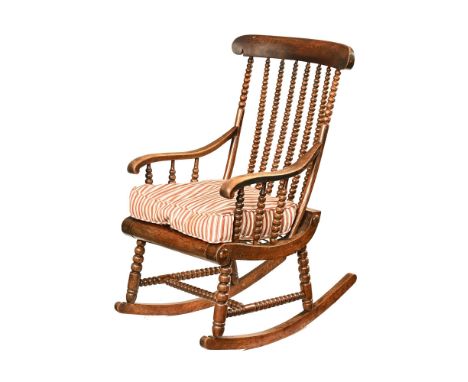 A Victorian bobbin turned rocking chair, with strung seat and later cushion.  Height +/- 105 cm, width at the arms 58 cm, sea