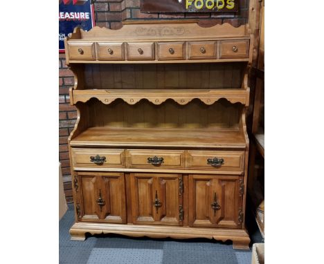 A kitchen dresser, two shelves, one of which contains two drawers, one drawer over three hinged doors, part mosaic tiled back