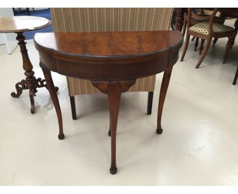 An early 20th century foldover mahogany card table with lobe shaped top on cabriole legs