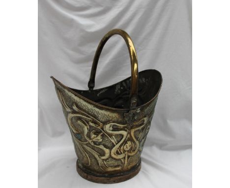 An Art Nouveau stamped brass coal scuttle, embossed with stylised flower heads and tendrils, with a swing handle, 33cm high 