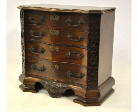 A miniature Chippendale style serpentine chest of four long graduated drawers flanked by blind fret-cut panels, raised on a m