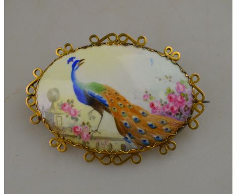 An oval ceramic brooch, painted with a peacock on a stone parapet, signed C. Gresley, including gilt metal surround, 4 x 5.5 