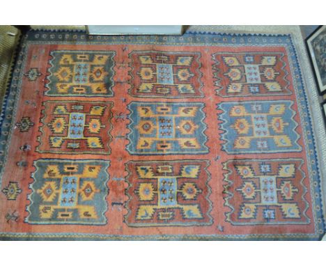 A Turkish carpet, the geometric panel design on pale red/terracotta ground, 280 x 213 cm