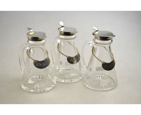 A set of three conical glass whisky drams with star-cut bases and silver collars and covers, each with its silver bottle-tick