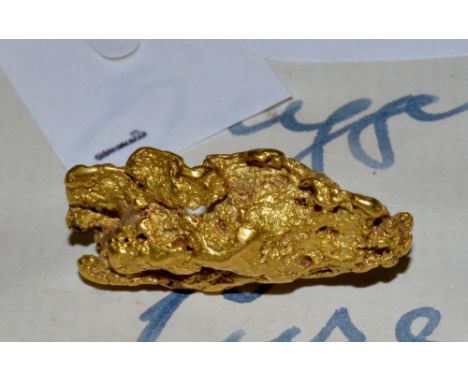 A gold coloured tie pin , mounted with a gold coloured nugget