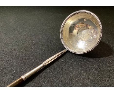 A George III silver toddy ladle, the bowl set with a George II shilling of 1747, twisted whale bone haft, 36.5cm long, c.1780