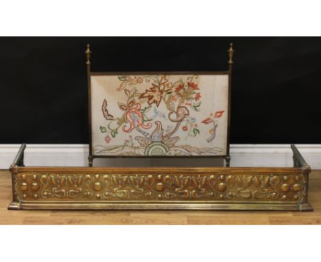 An embossed brass fender, 128cm wide; a Regency style brass and tapestry fire screen, spire finials, 63cm wide (2) 