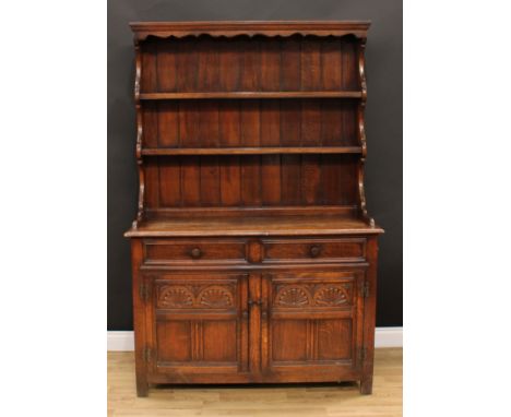 An 18th century style oak dresser, moulded cornice above a shaped apron and two plate racks, the base with two short drawers 