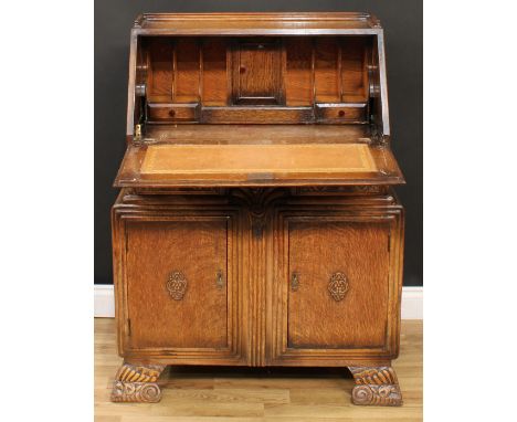 An Art Deco oak bureau, fall front enclosing a tooled and gilt writing surface, small door, pen rest, pigeonholes and small d