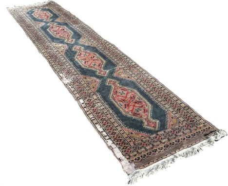 A Persian runner with four extended lozenges on a pale blur ground, with a signature 370cm by 80cm