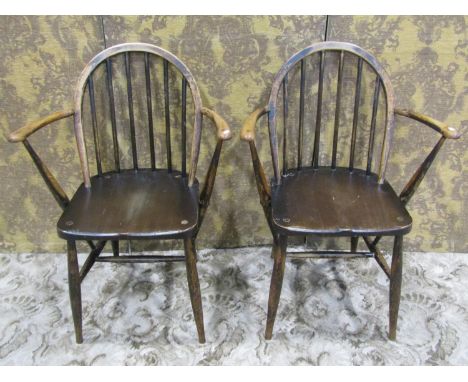A pair of vintage Ercol stained beechwood hoop and stick back open elbow chairs with original blue printed labels 