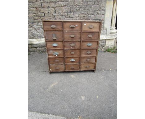 A vintage rustic stained pine bank of eighteen small drawers, 93 cm high x 90 cm wide x 50 cm deep (af)