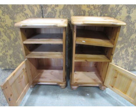 A matched pair of stripped pine bedside cupboards each partially enclosed by a fielded panelled door beneath a single adjusta