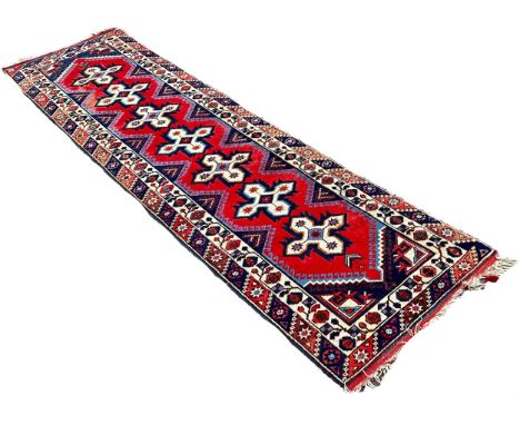 A Kazak type runner with seven star medallions on a red ground, 300cm x 80 cm