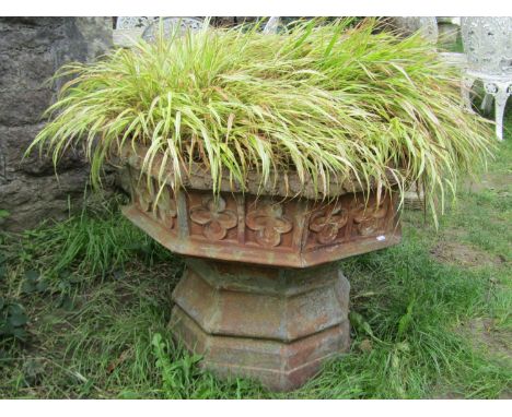 A large weathered cast iron font/ planter of octagonal form with gothic tracery detail (planted), 68 cm high x 85 cm wide