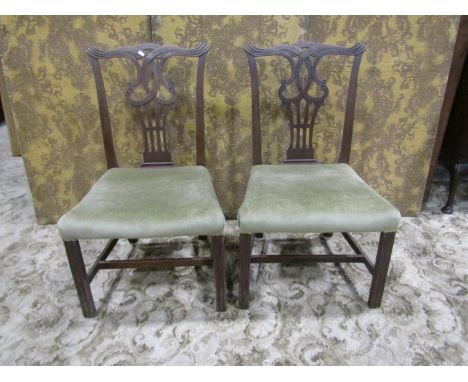 A pair of Georgian mahogany dining chairs in the Chippendale style with pierced and scrolled splats over upholstered seats ra