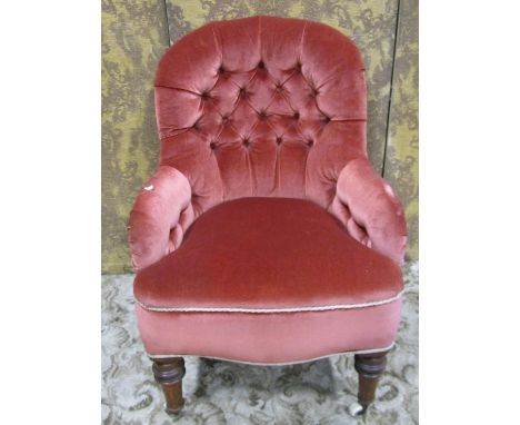 A Victorian drawing room chair with buttoned upholstery and shaped outline raised on turned tapered forelegs with ceramic cas