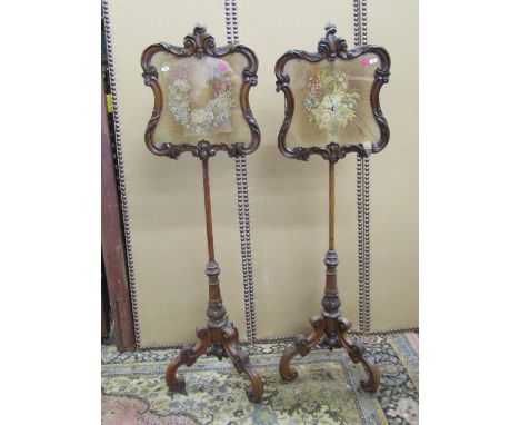 A pair of Regency pole screens rosewood framed each enclosing a petite point floral tapestry, the framework with carved detai