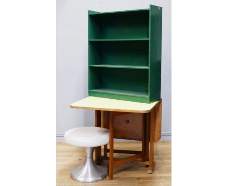 A Formica topped beech gate leg table, a green painted bookshelf and a footstool. 