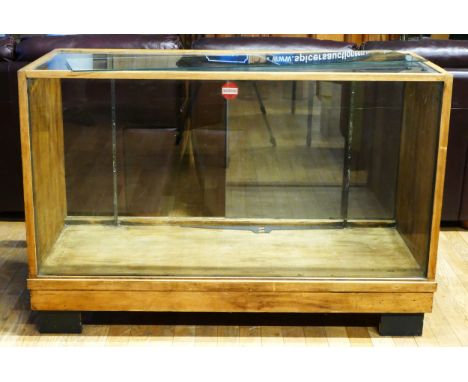 A 1930's light oak shop display unit with one glass shelf, sliding doors, 136 x 59 x 92cm. 