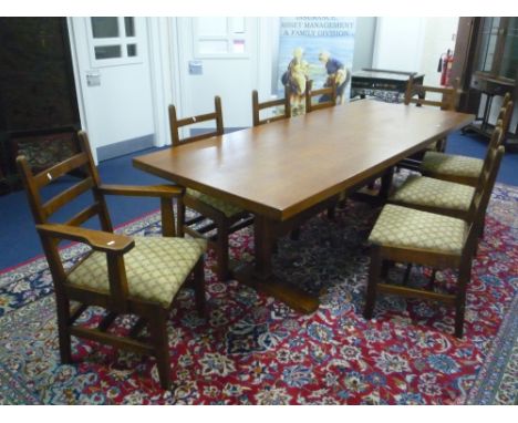 A LARGE OAK DINING TABLE AND TEN LADDER BACK CHAIRS, with fixed drop in upholstered seat pads, oak tree emblem carved to each