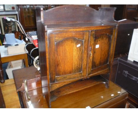 A SMALL OAK BOW FRONTED TWO DOOR CABINET, with lower shelf