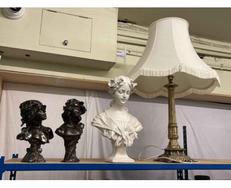 Three ornate busts and a brass table lamp.