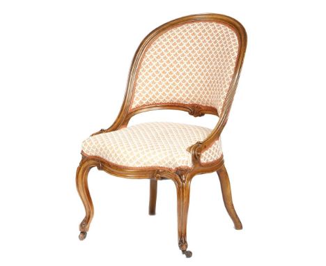 A Victorian walnut nursing chair, with a moulded frame and a padded back and seat, on cabriole front legs and ceramic castors