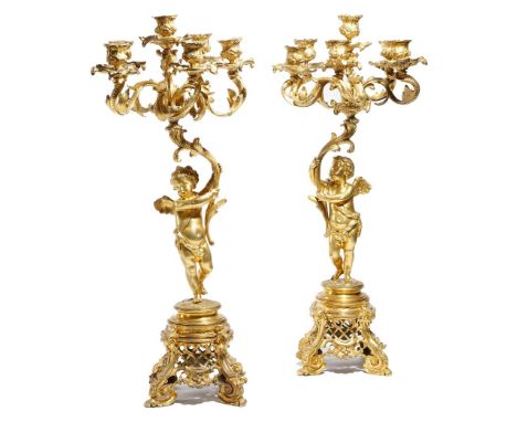 A pair of Napoleon III ormolu figural six-light candelabra in Louis XV style, each with a winged cherub supporting a leaf cor