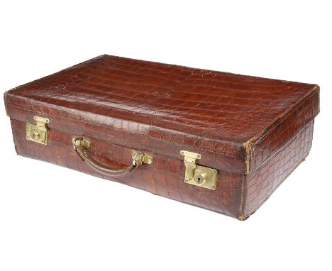 An early 20th century crocodile leather suitcase by Army & Navy, the hinged lid with gilt initials 'B. S.' with a later lined