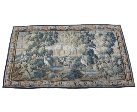 An 18th century Aubusson or Flemish verdure tapestry, worked with a château with mountains in the distance, framed by trees b