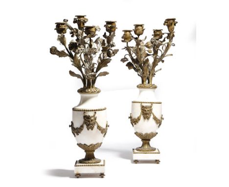 A pair of French white marble and gilt brass mounted candelabra in Louis XVI style, the urn body applied with satyr masks and