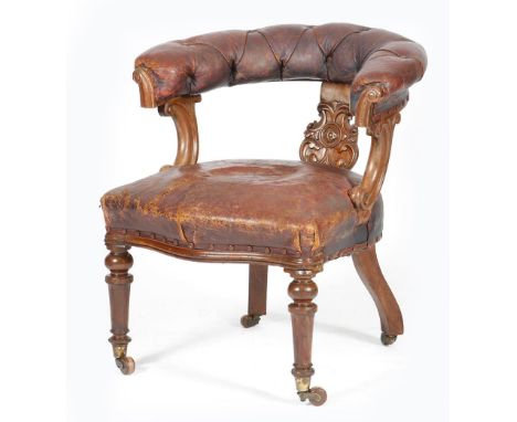 A Victorian mahogany desk chair, button upholstered with maroon leather, the splat carved with scrolls, with a serpentine fro