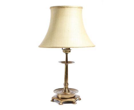 A brass altar style candlestick table lamp, the bowl top above two reeded drip-pans, on a hexagonal base, with stylised feet,