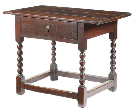 An early 18th century oak side table, the boarded top with cleated ends, above a frieze drawer, on bobbin turned legs united 