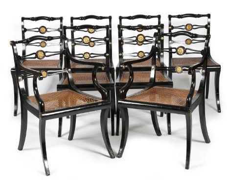 A set of eight Regency ebonised dining chairs by John Gee, each with a pierced ladder back inset with a gilt rosette, above a