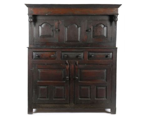 An early 18th century Welsh oak press cupboard, the plain frieze with turned pendants, above a pair of arched fielded panel d