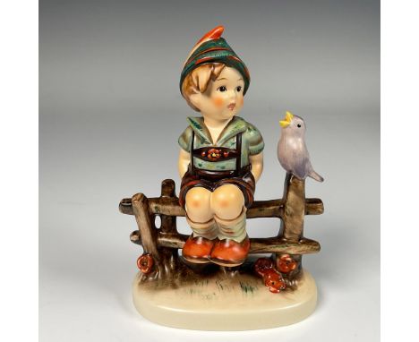 Hand decorated figure of a Bavarian boy rests on a wooden fence while being entertained by a chirping songbird. Artist impres