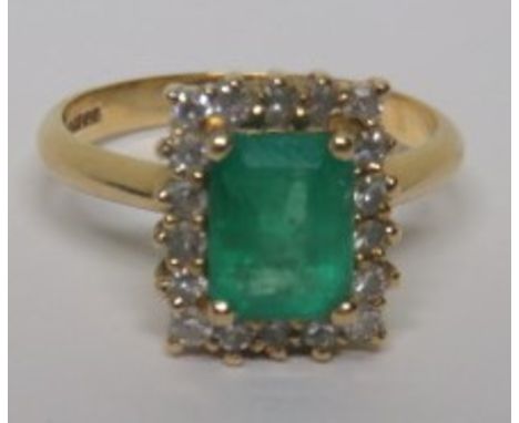 A marked 750 gold diamond and emerald cluster ring, with the step cut emerald measuring approximately 8.6mm x 5.93mm, prong s