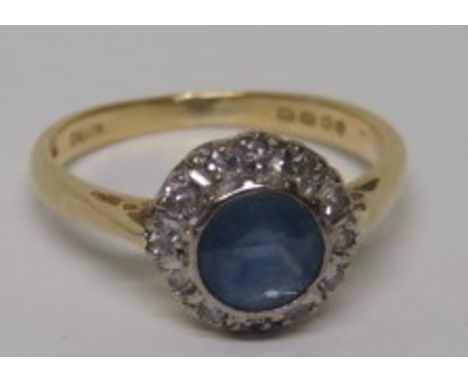 An 18ct gold diamond and light cornflower blue sapphire halo ring, with faded hallmarks, the sapphire measuring approximately